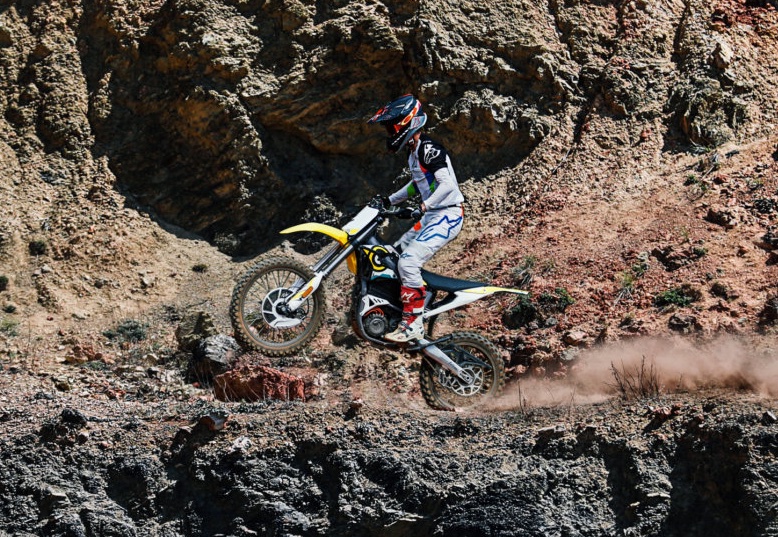 motorbike rider on yellow sur-ron storm in rough terrain