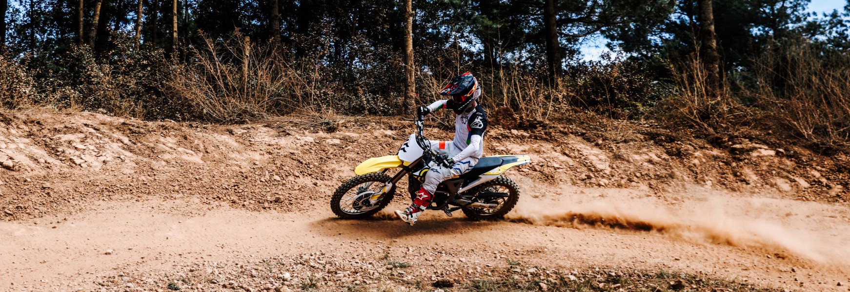motorbike racing rider competing on yellow sur-ron storm in rough terrain
