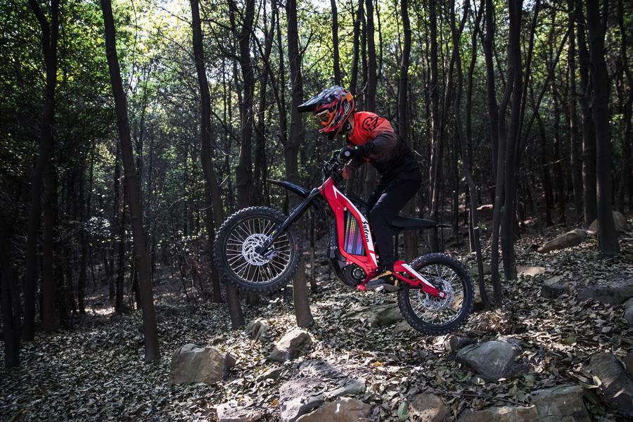 motorbike rider on red sur-ron doing a wheelie off road